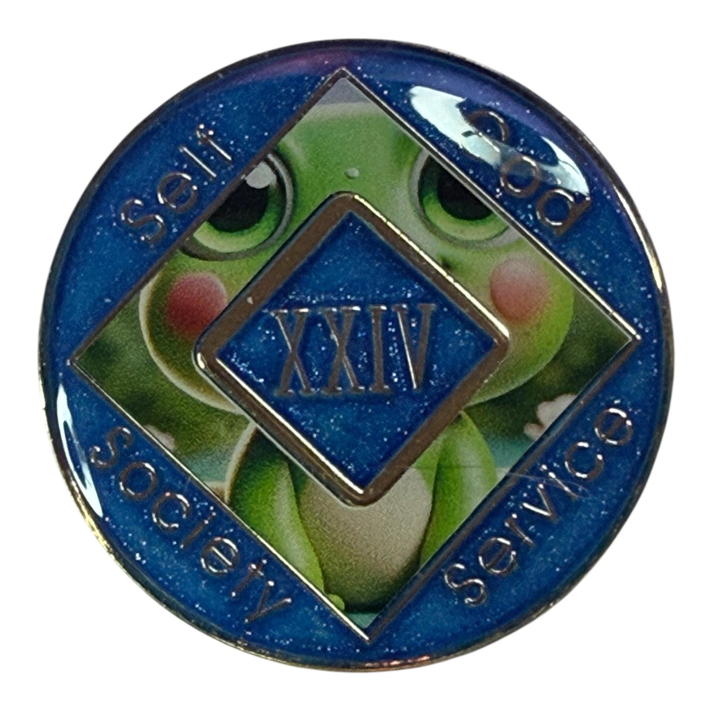 Narcotics Anonymous 24-year recovery medallion with a cute cartoon frog design and blue glitter background. Features the NA diamond symbol with âSelf, God, Society, Serviceâ around the edges, representing growth, transformation, and long-term sobriety in recovery. Perfect anniversary coin for celebrating 24 years clean.