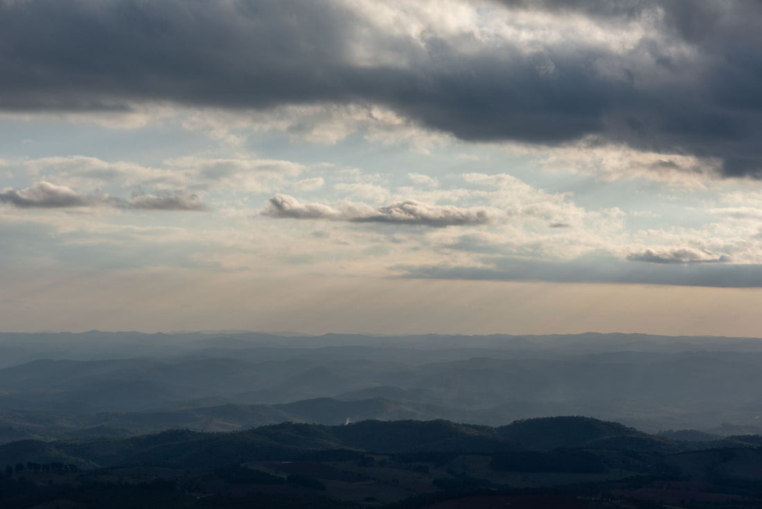 Rolling green mountain ridges beneath dramatic clouds in Minas Gerais, Brazil.