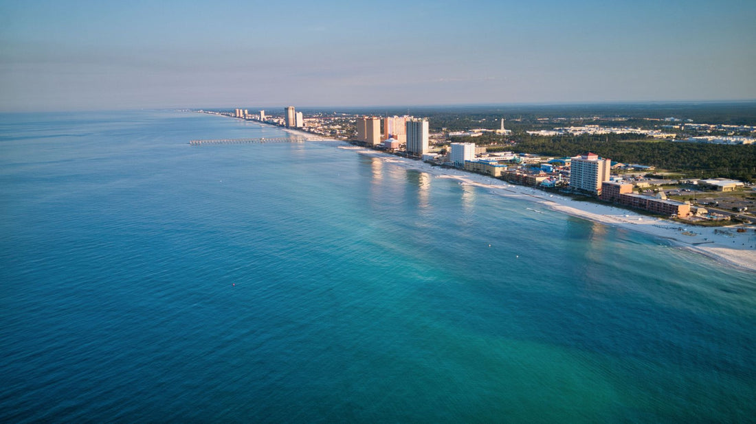Aerial view of Panama City Beach with turquoise Gulf water, white-sand shoreline and beachfront buildings.