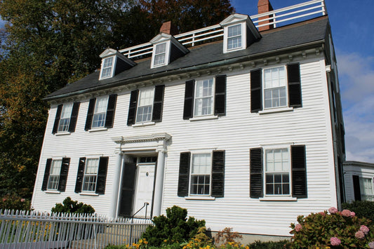 Historic white colonial house with black shutters and a white picket fence in Salem, Massachusetts.