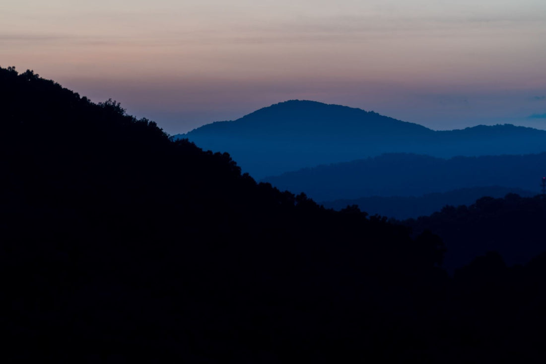 Layered Blue Ridge Mountain ridges near Asheville beneath a warm golden-hour sky.