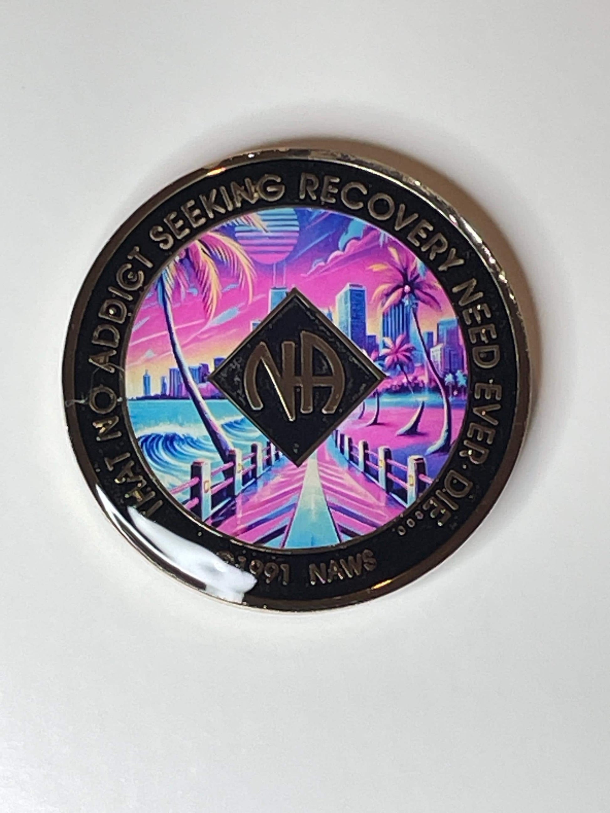Narcotics Anonymous Miami-themed recovery medallion featuring a vibrant retro sunset cityscape with palm trees, ocean pier, and the NA logo, symbolizing serenity, renewal, and the journey of recovery.