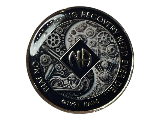 Narcotics Anonymous medallion with black and silver gear and motorcycle engine design, featuring the NA symbol and the quote ‘That No Addict Seeking Recovery Need Ever Die,’ symbolizing strength, unity, and progress in recovery.