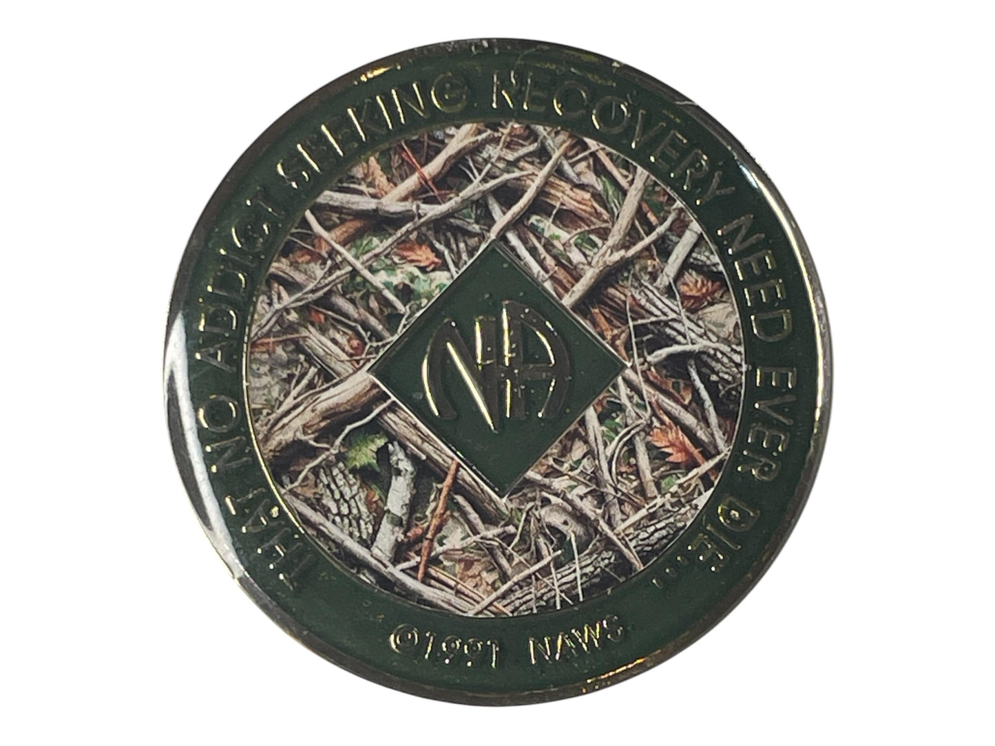 Narcotics Anonymous recovery medallion featuring a camouflage-style forest floor background with branches, twigs, and leaves, symbolizing strength, resilience, and grounding in recovery. The medallion has a deep green metallic border engraved with “That No Addict Seeking Recovery Need Ever Die,” with the NA logo in the center, representing unity and perseverance through nature’s balance.