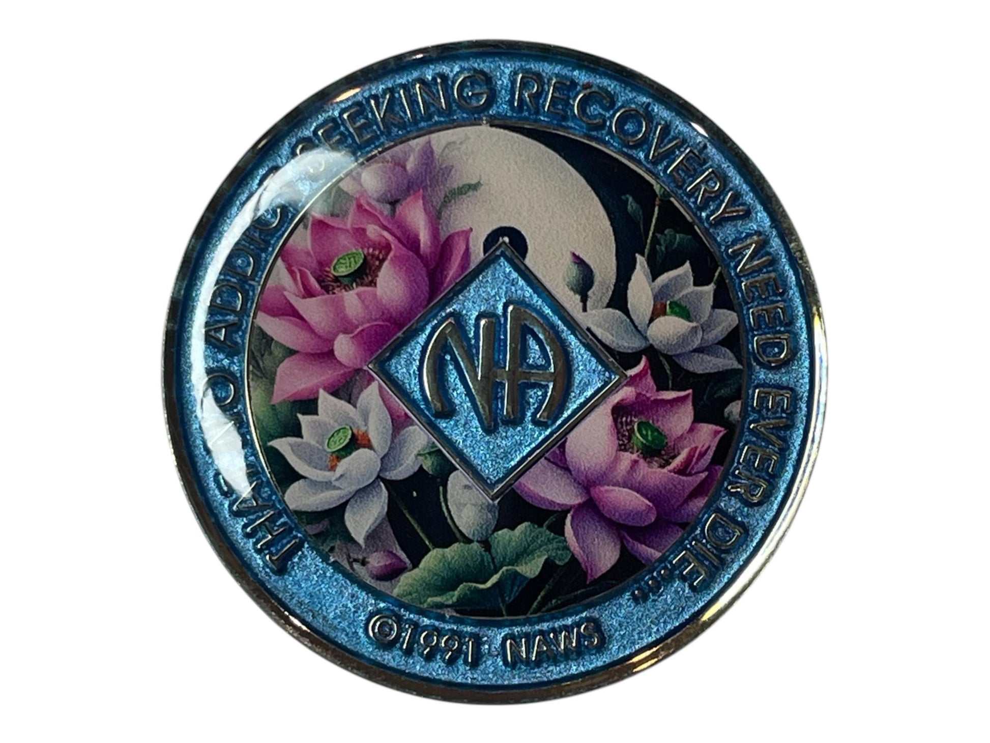 Narcotics Anonymous recovery medallion with shimmering blue border, NA diamond logo, and lotus flower design under a moon, featuring the phrase ‘That No Addict Seeking Recovery Need Ever Die