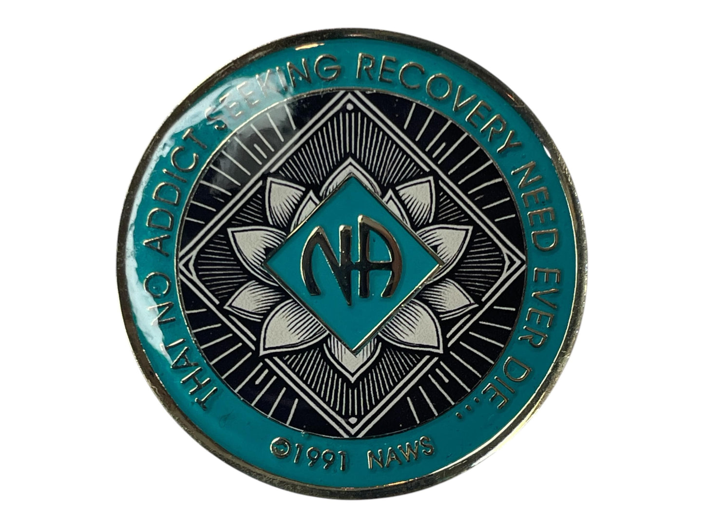 Narcotics Anonymous teal and black recovery medallion featuring a radiant lotus flower design with the NA logo in the center, symbolizing spiritual awakening, purity, and transformation in sobriety. Inscribed with “That No Addict Seeking Recovery Need Ever Die” and ©1991 NAWS.