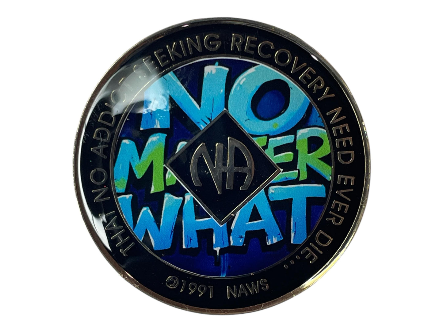 Round Narcotics Anonymous recovery medallion with blue and green graffiti-style text that reads ‘No Matter What’ around the NA symbol, with the words ‘That no addict seeking recovery need ever die’ along the border.