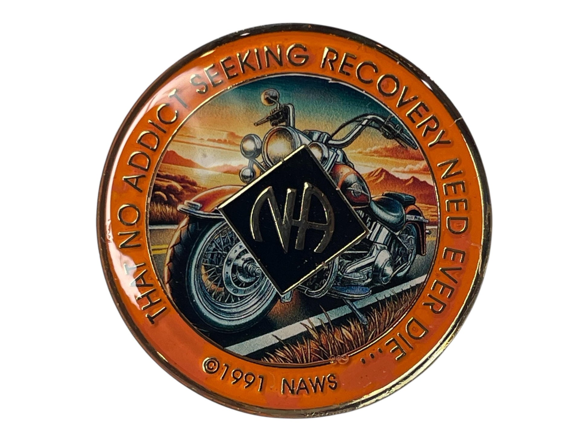 Narcotics Anonymous motorcycle recovery medallion featuring a classic bike at sunset with mountains in the background, orange border, and the quote “That No Addict Seeking Recovery Need Ever Die,” symbolizing freedom, strength, and the journey of sobriety.