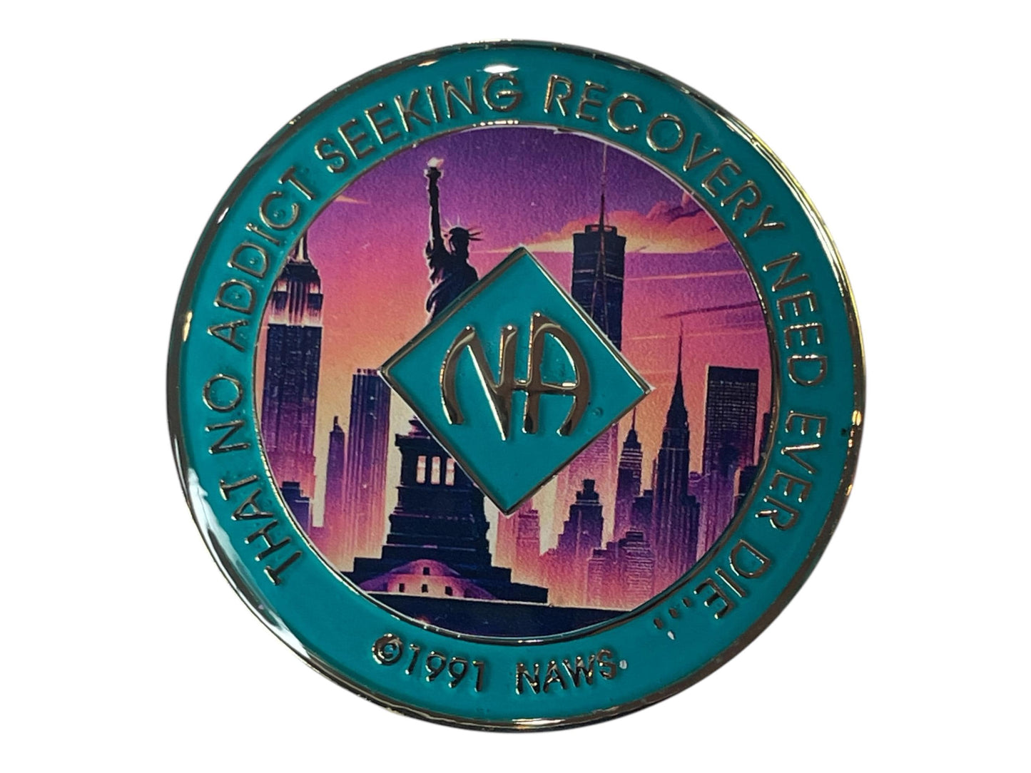Narcotics Anonymous recovery medallion featuring the Statue of Liberty and New York City skyline at sunset, symbolizing freedom and new beginnings, with teal border and the quote “That No Addict Seeking Recovery Need Ever Die.”
