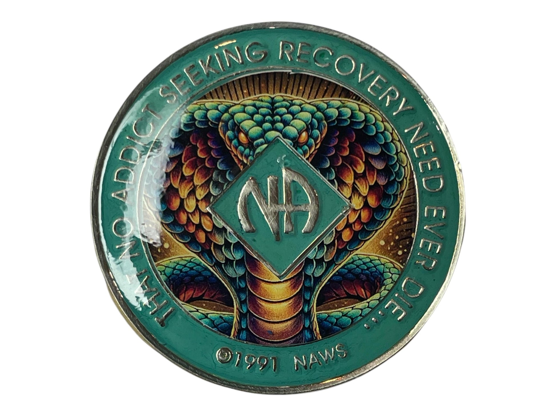 Narcotics Anonymous cobra medallion featuring a detailed, colorful snake design with teal border and NA logo in the center, surrounded by the phrase “That No Addict Seeking Recovery Need Ever Die,” symbolizing transformation, strength, and rebirth in recovery.