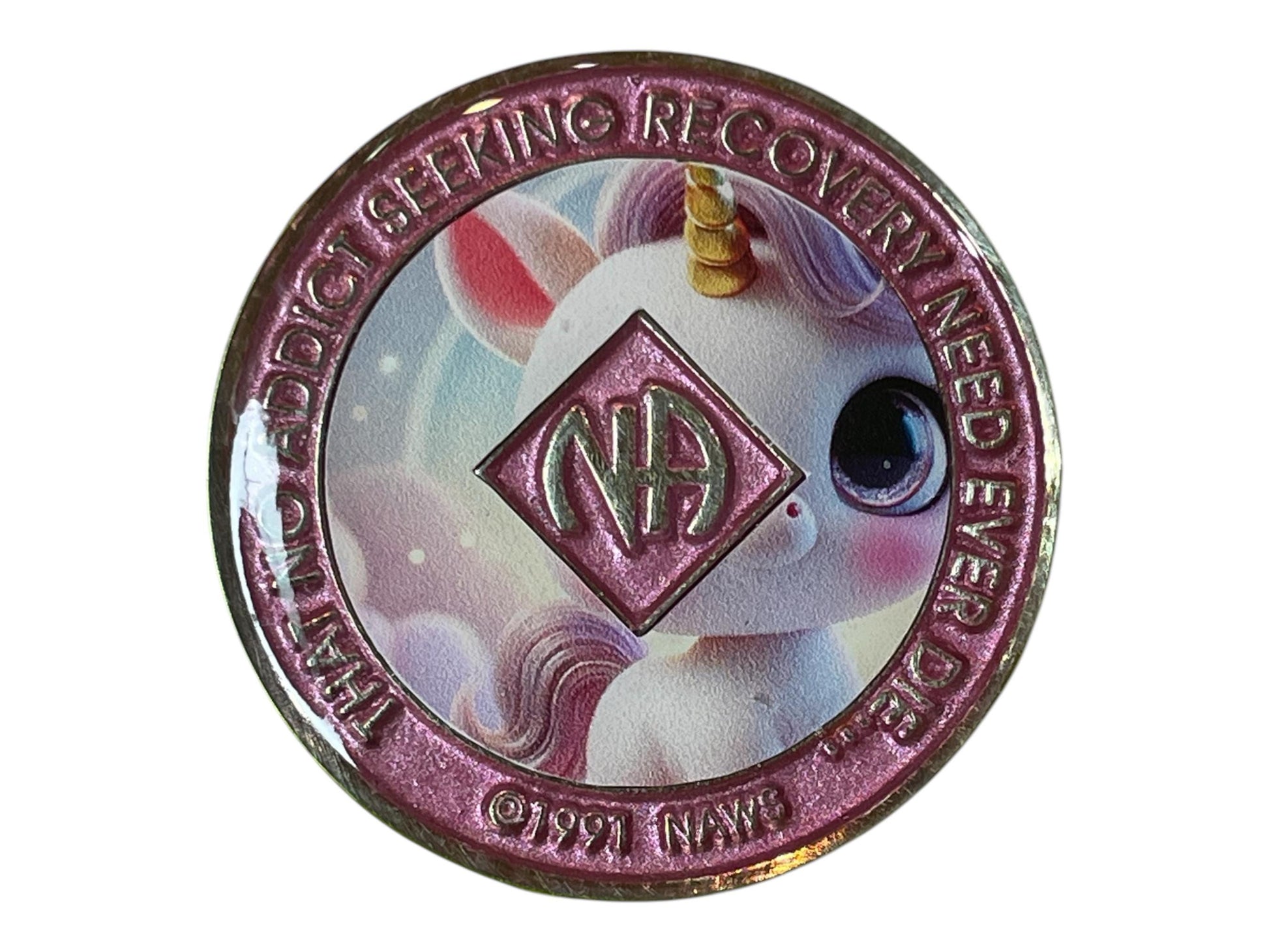 Narcotics Anonymous recovery medallion featuring an adorable pastel unicorn design, symbolizing hope, innocence, and the magic of transformation in recovery. The medallion has a shimmering pink border with the NA logo at the center and the words “That No Addict Seeking Recovery Need Ever Die,” representing healing, positivity, and renewed life on the journey of sobriety.