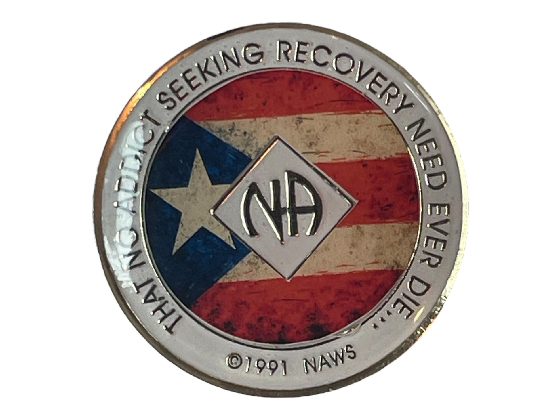 Narcotics Anonymous recovery medallion featuring a rustic Puerto Rican flag background, symbolizing pride, unity, and strength in recovery. The design includes the NA logo at the center with a silver border engraved with the phrase “That No Addict Seeking Recovery Need Ever Die,” representing hope, perseverance, and community for members celebrating their clean time.