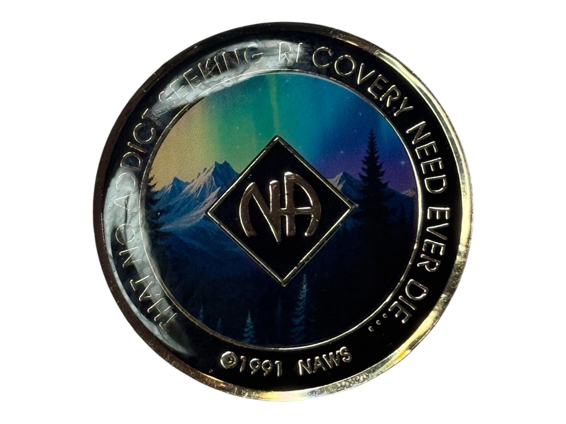 Narcotics Anonymous recovery medallion featuring a breathtaking aurora borealis design over a mountain landscape with silhouetted pine trees, symbolizing hope, spiritual awakening, and the beauty of recovery. The medallion has a black metallic border engraved with “That No Addict Seeking Recovery Need Ever Die,” and the NA logo at the center, representing serenity and renewal under the northern lights.