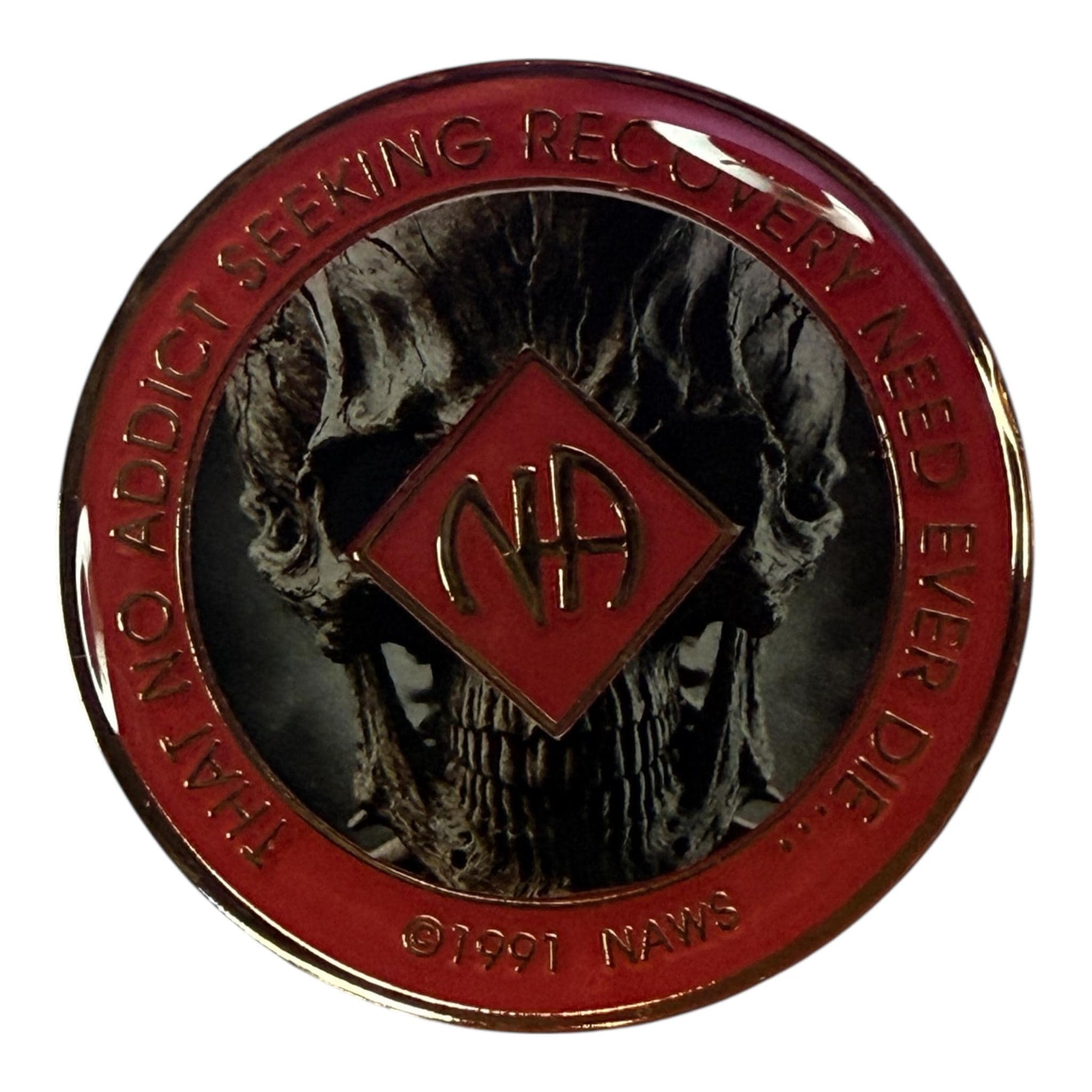 Narcotics Anonymous recovery medallion featuring a detailed skull design with a red enamel border and metallic finish. The NA logo is centered with the phrase “That No Addict Seeking Recovery Need Ever Die,” representing transformation, courage, and strength through addiction recovery.
