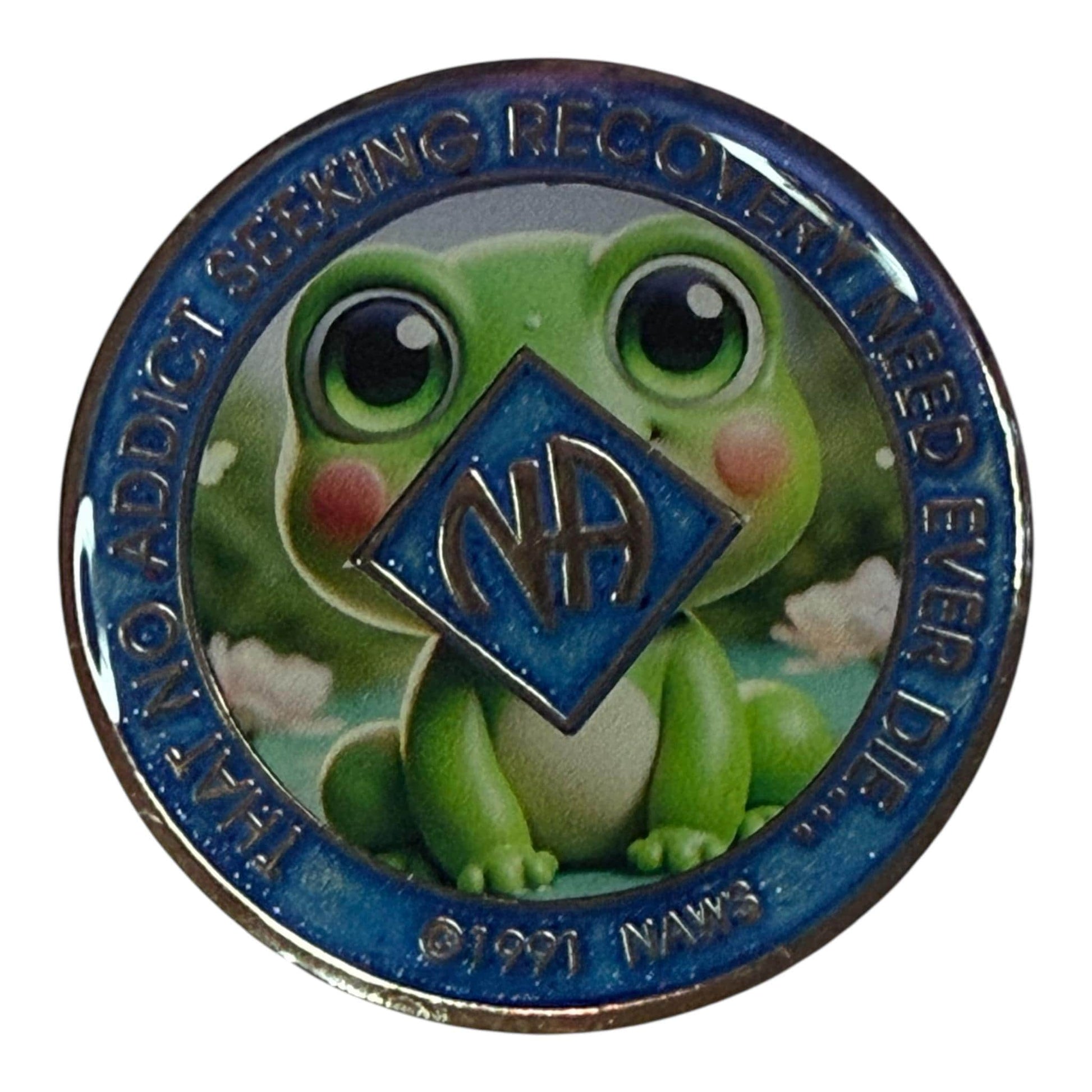 Narcotics Anonymous recovery medallion featuring a cute cartoon frog with big eyes and a blue NA logo at the center. The coin includes the quote “That No Addict Seeking Recovery Need Ever Die,” symbolizing hope, renewal, and new beginnings in sobriety. Perfect for celebrating milestones in addiction recovery.
